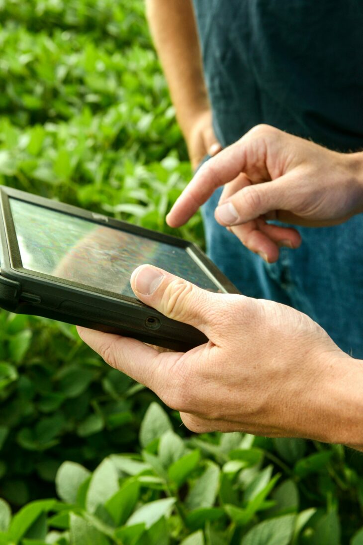Hands holding a tablet showing precision ag software