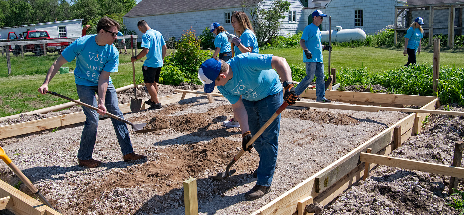 Group of people wearing volunteer shirts working in a community garden together